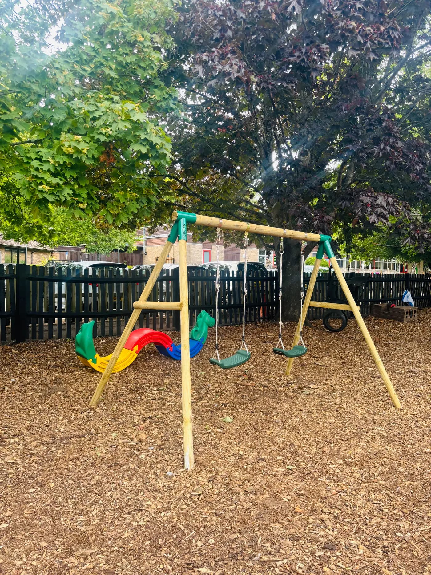 The swing set beneath mature maple trees at Blue Nest Montessori Aldershot