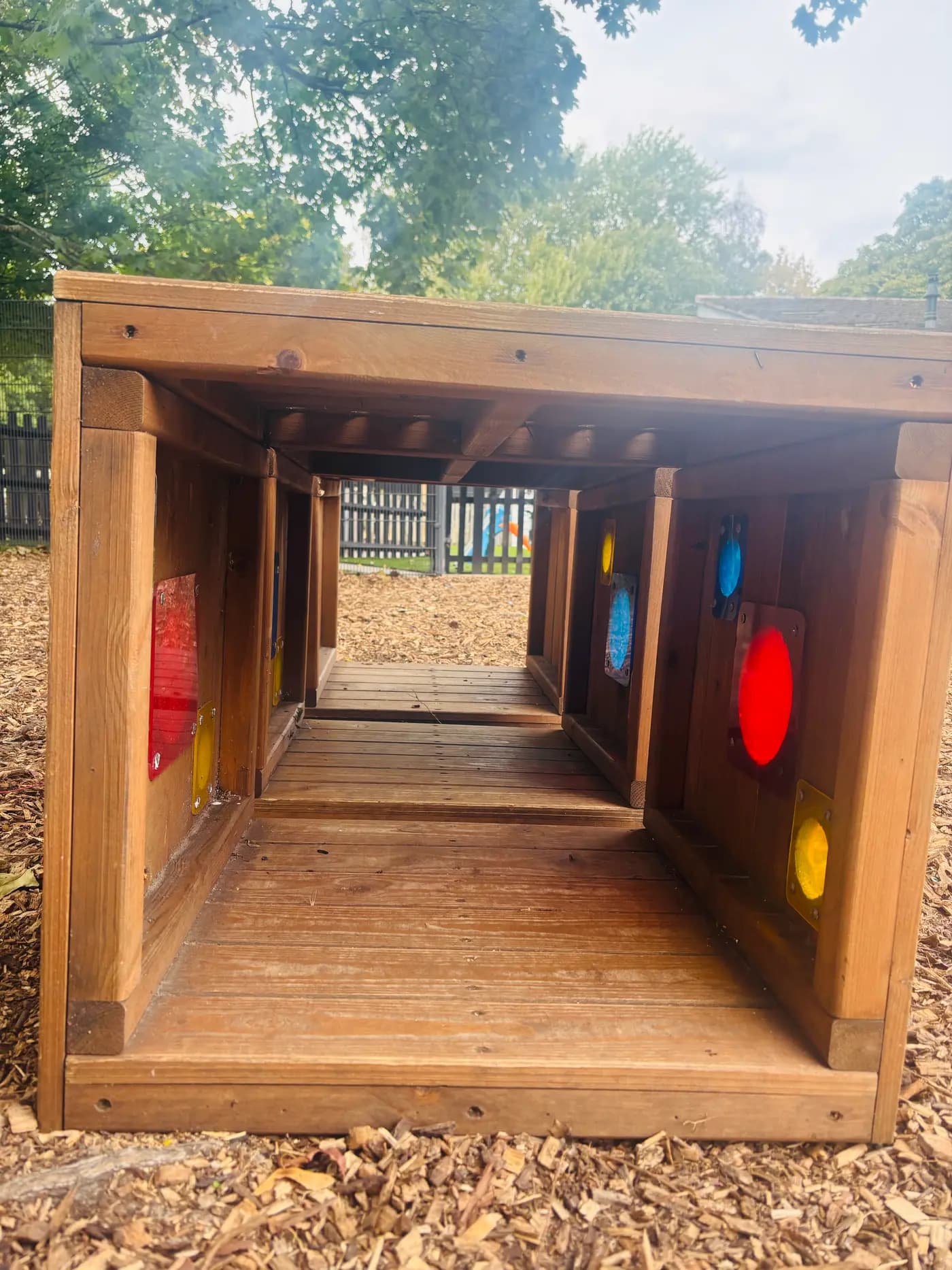 A wooden sensory play tunnel with coloured acrylic windows at Blue Nest Montessori Aldershot