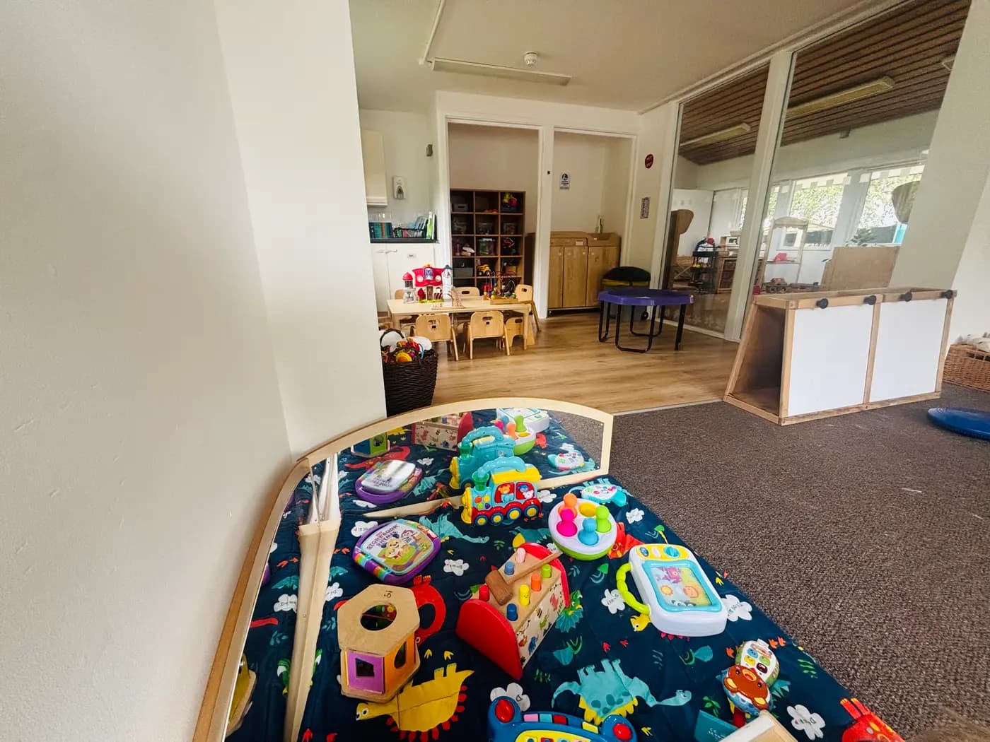 The baby room play mat with toys, looking through to the toddler room at Blue Nest Montessori Aldershot