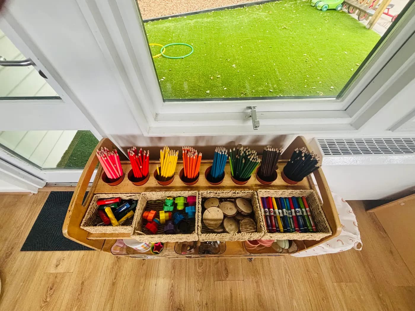 Colour-sorted pencil pots, crayons and craft baskets by the garden door at Blue Nest Montessori Aldershot