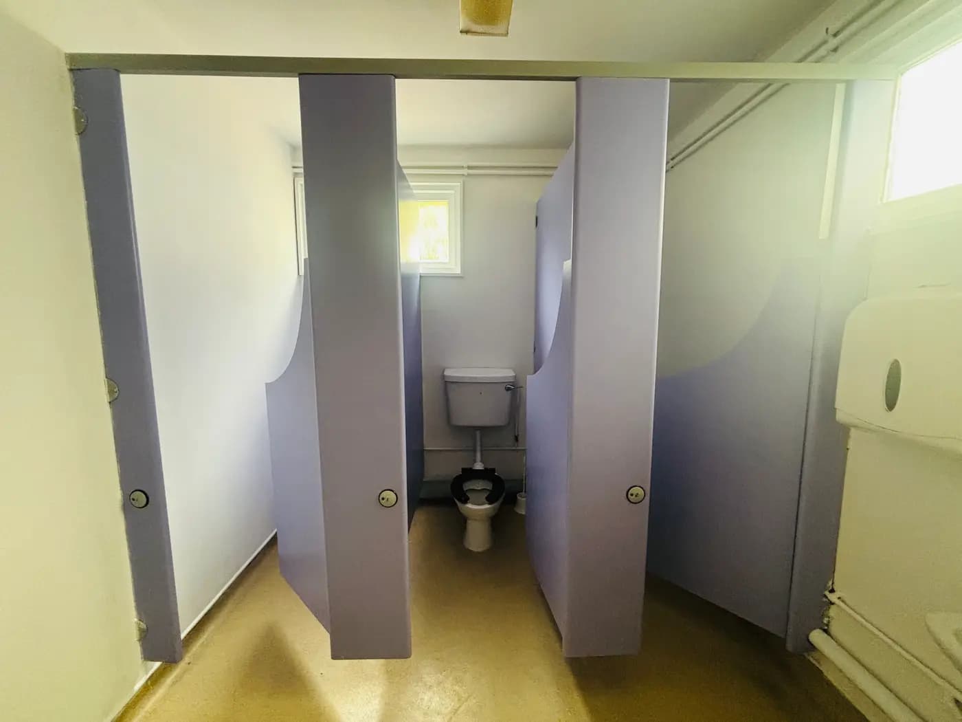 The child-sized washroom with low toilets and lilac cubicle doors at Blue Nest Montessori Aldershot