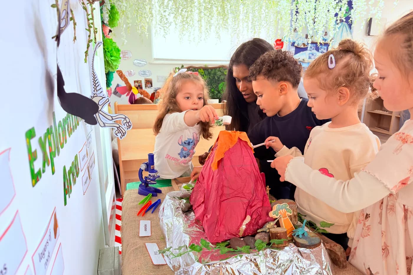Children investigating the volcano experiment by the Explore board at Blue Nest Montessori Borehamwood