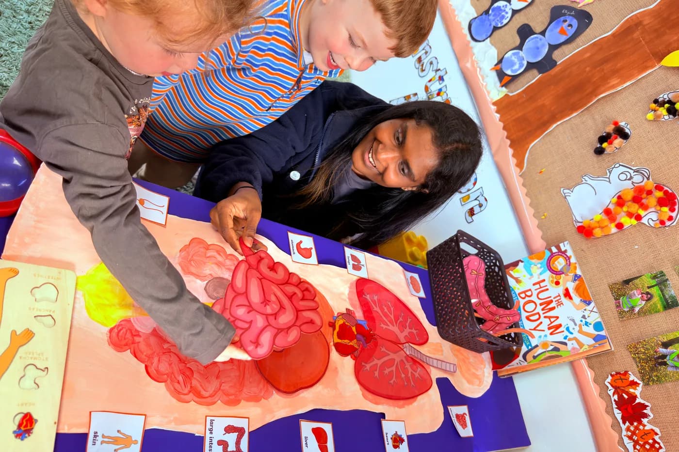 Children and a practitioner exploring the human body organs learning mat at Blue Nest Montessori Borehamwood