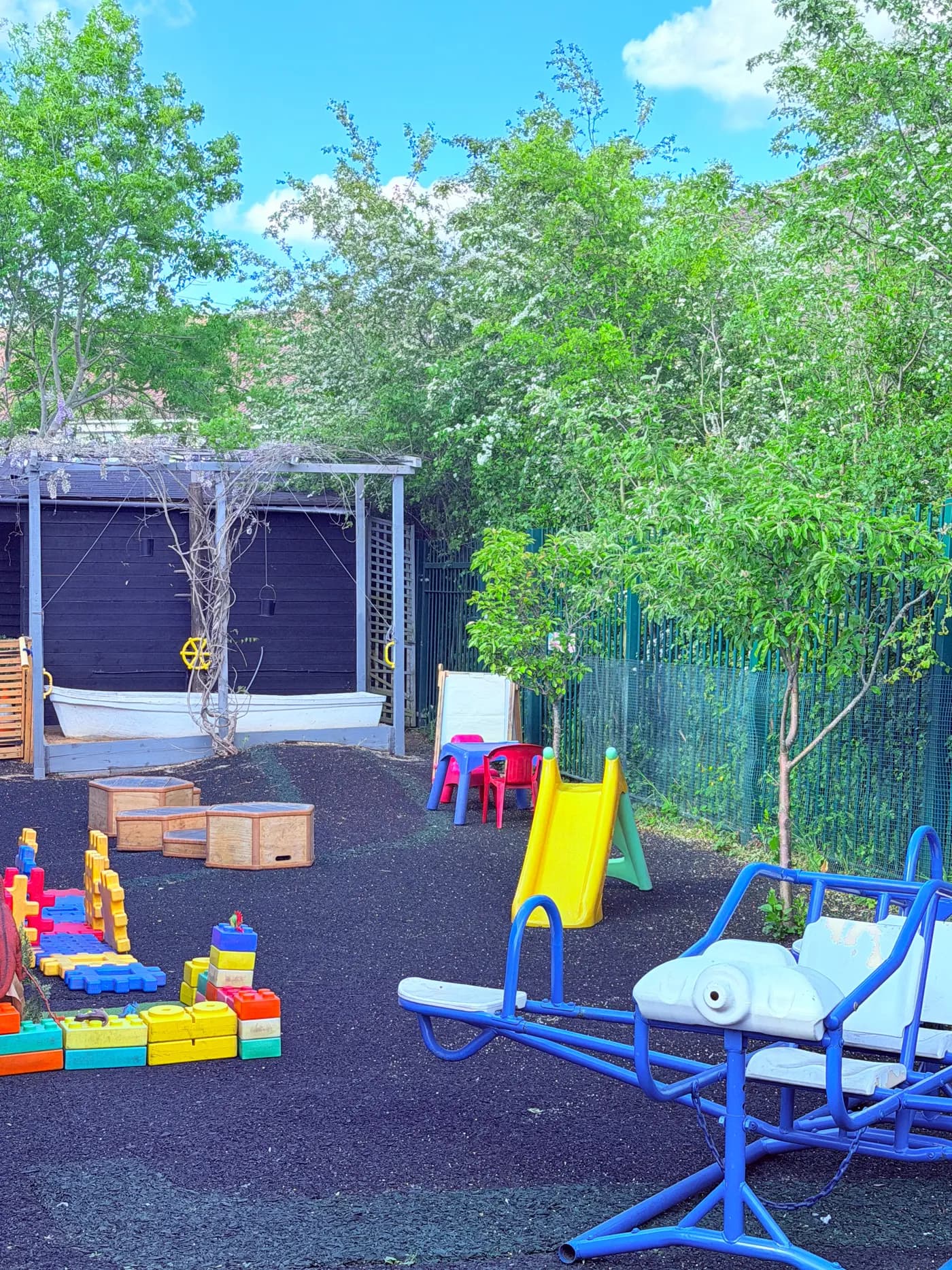 The outdoor play area with a slide, climbing toys and pergola at Blue Nest Montessori Harrow