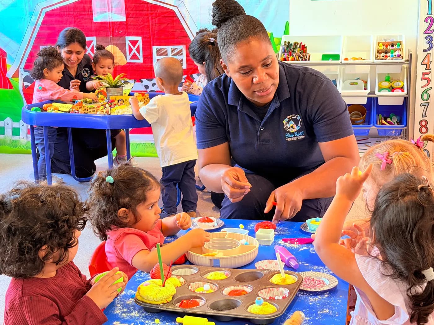 An educator guiding two children through a tabletop Montessori activity at Blue Nest Montessori Harrow
