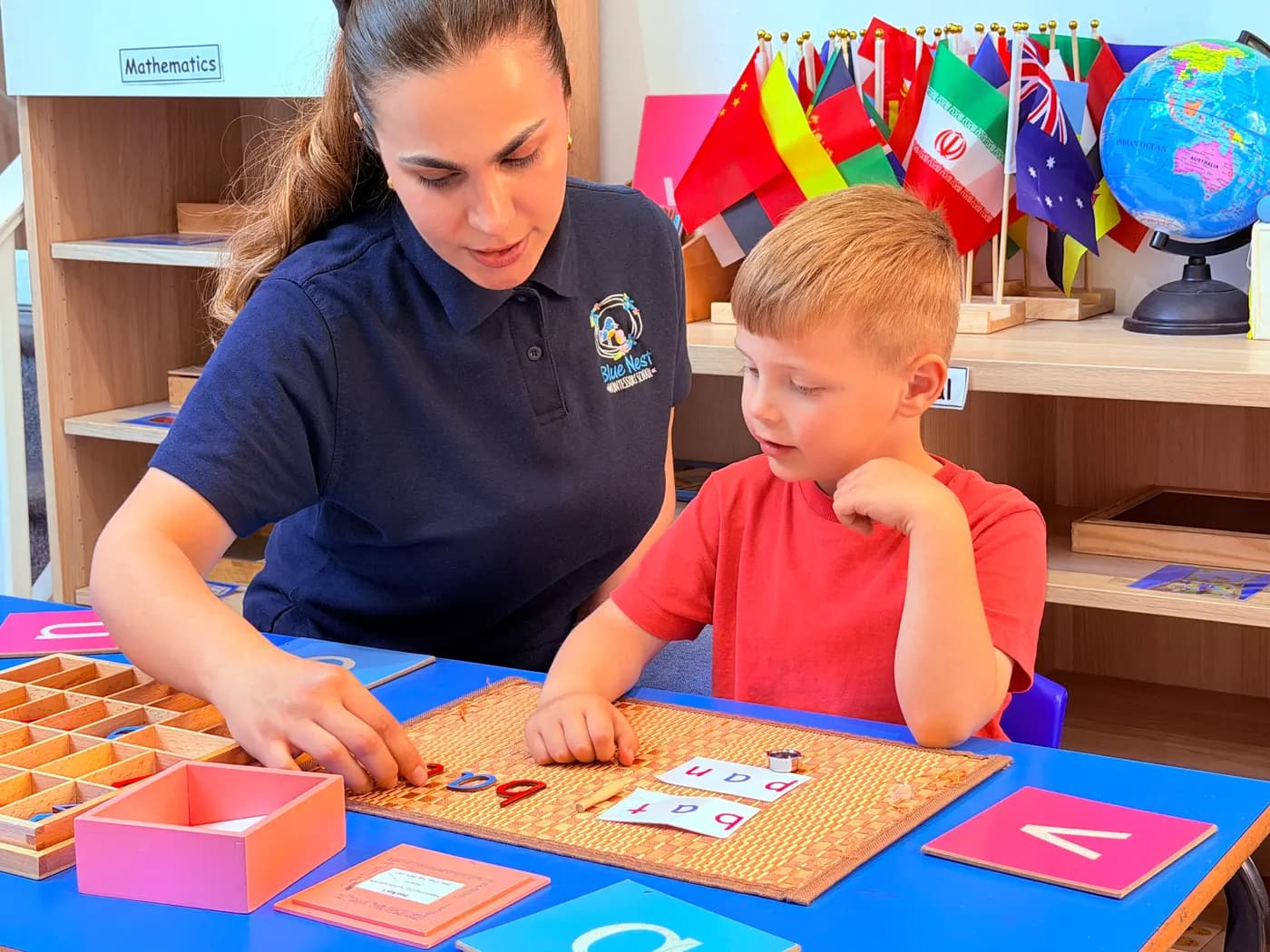 An educator supporting a small group at the activity table at Blue Nest Montessori Harrow