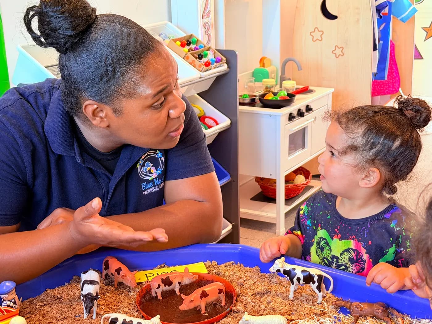 Educator supporting a toddler at a sensory tray at Blue Nest Montessori Harrow
