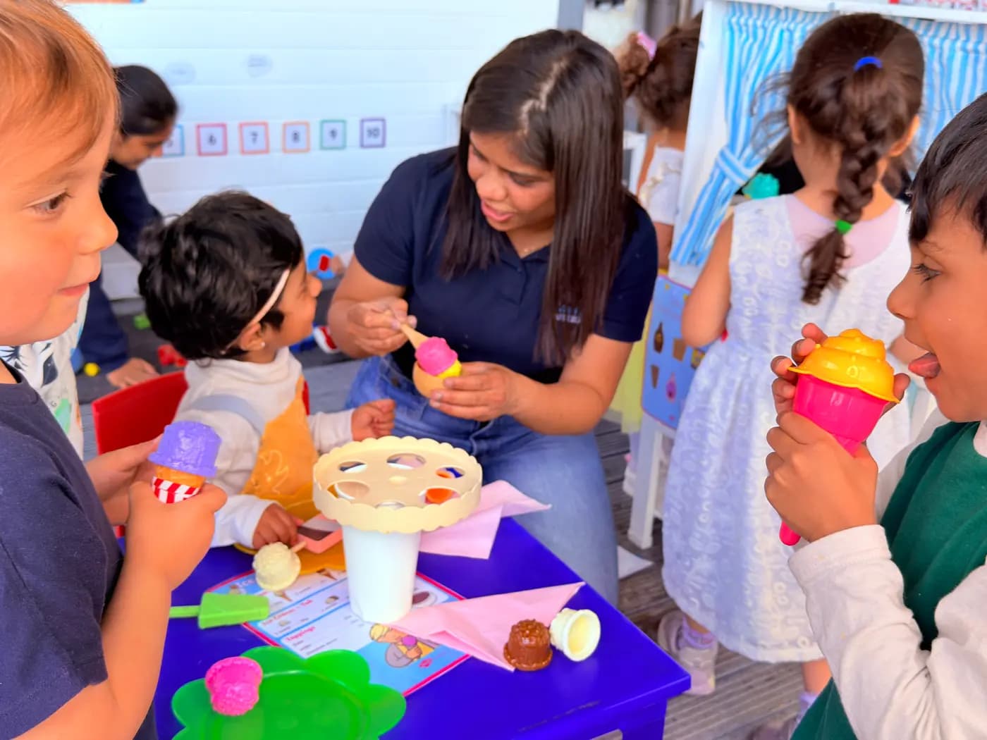 Children enjoying an ice-cream parlour role-play with an educator at Blue Nest Montessori Harrow