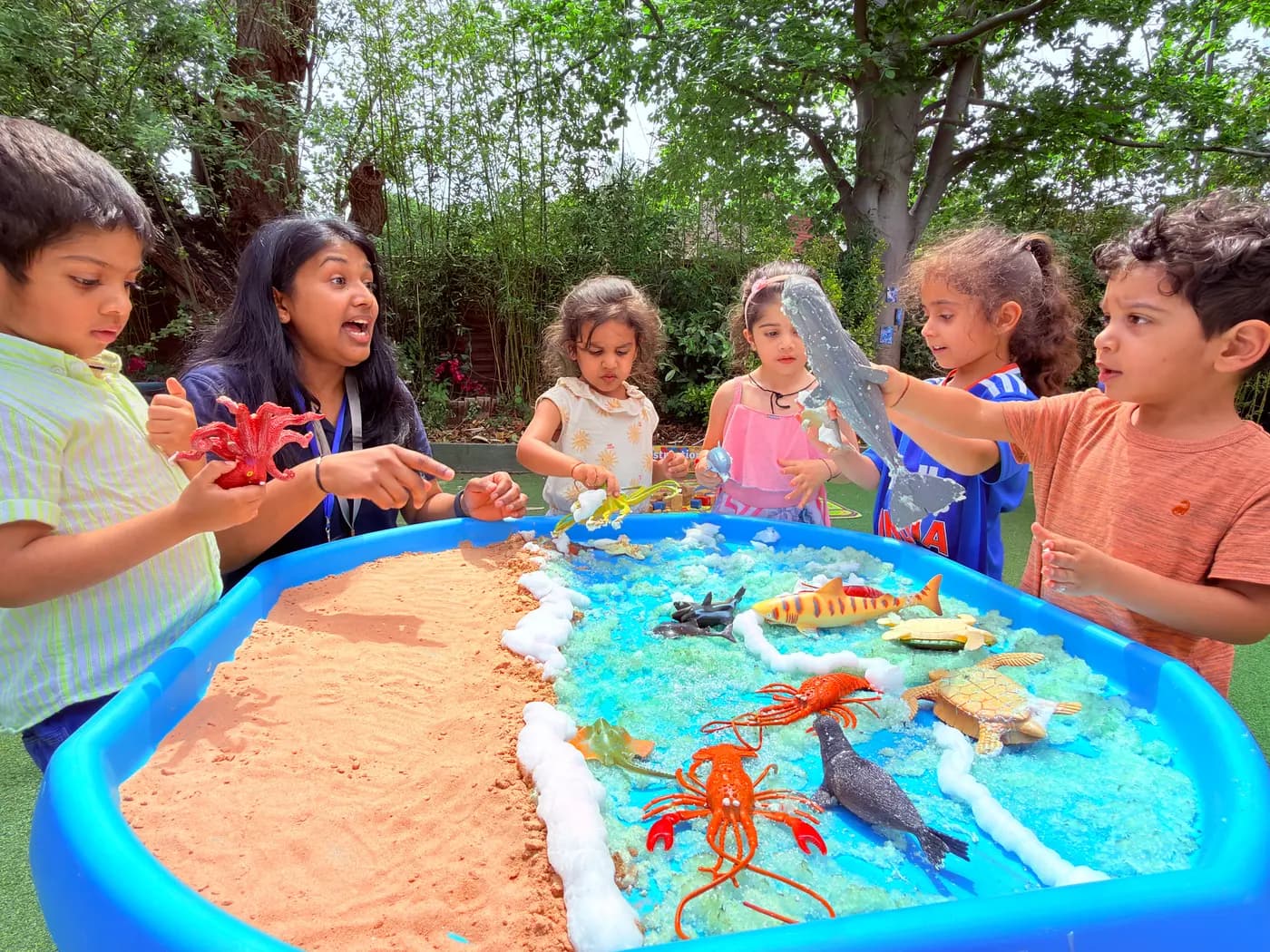 Children gathered around the outdoor water-play table at Blue Nest Pinner