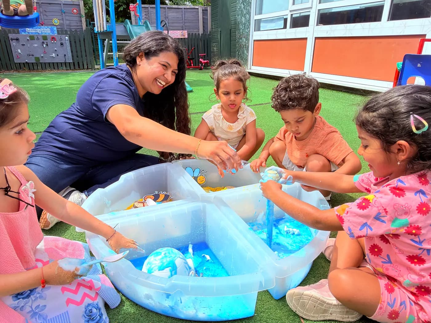 An educator and children at the outdoor water-play table at Blue Nest Pinner