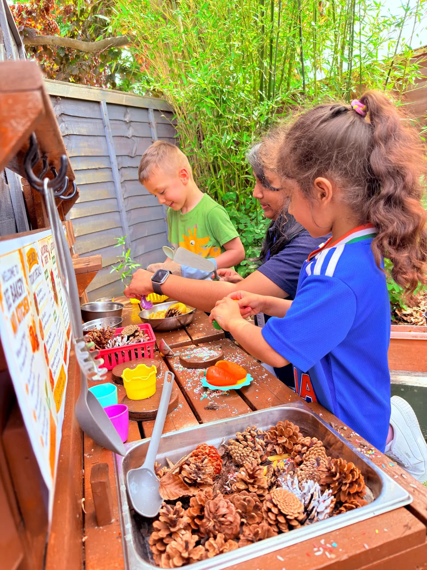 Children at the outdoor Mud Cafe mud-kitchen station at Blue Nest Pinner