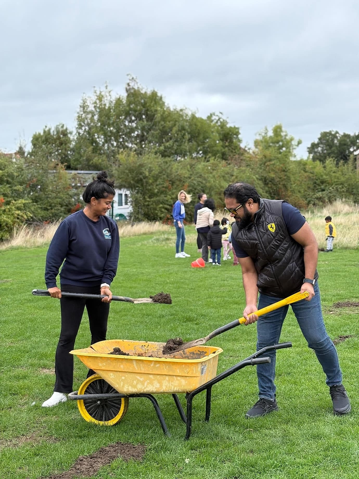 Volunteers loading soil into a wheelbarrow on the green
