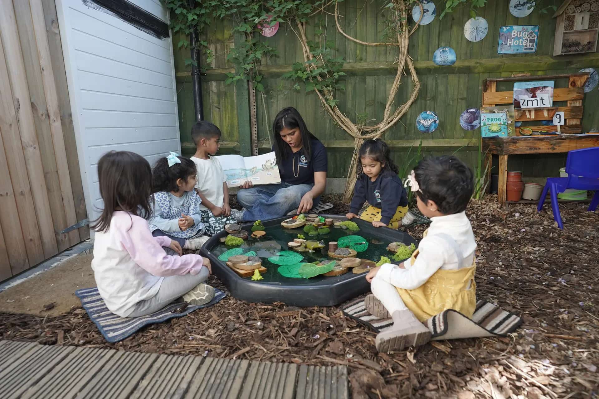 A Blue Nest practitioner leading an outdoor learning session with a group of children